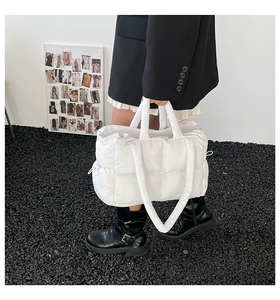 Detailed side view of white quilted down tote bag with nylon texture in outdoor setting