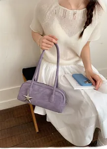 Detail of purple faux leather handbag with silver star pendant on white outfit
