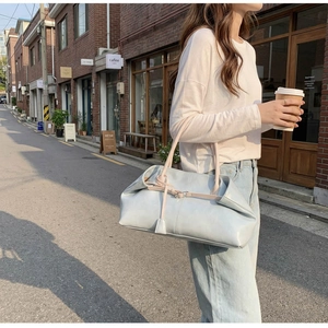 Sac cabas chic en cuir bleu clair avec anses roses dans une scène de style urbain