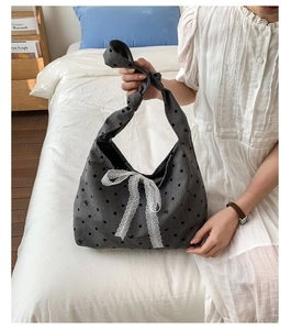 Macro detail of casual grey canvas tote bag with black polka dots and white lace bow