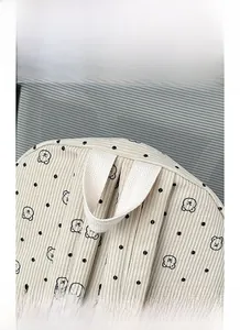 Detailed view of the reinforced white ribbon handle on a beige corduroy bear print backpack