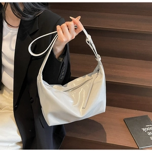 Detail of grey glossy leather hobo bag with adjustable strap worn by a model