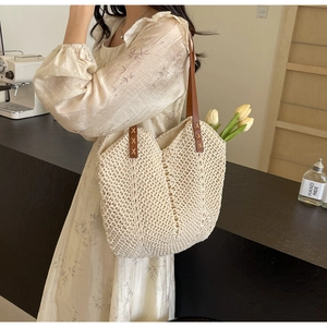 Detail of woven tote bag with dark brown leather strap and decorative stitching