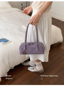 Close-up of purple suede bowling bag featuring long straps and starfish metal charm detail