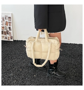 Detail of off-white quilted puffer bag showing nylon texture and adjustable side drawstring