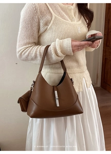 Detail shot of a brown leather bucket bag featuring a silver piston clasp and small pouch