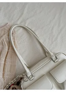 Detail view of white shoulder bag with dual front pockets and silver metal buckles