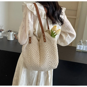 Detail of hand-woven off-white tote bag with brown leather straps and X-shaped stitching