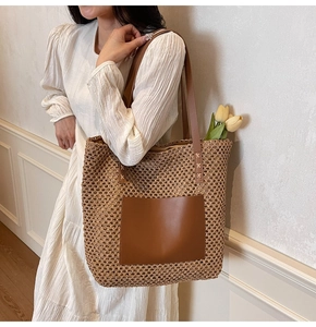 Detail of hand-woven straw tote bag featuring a large brown leather pocket and tulip accent