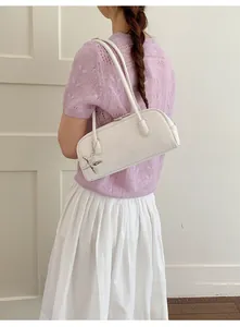 White leather bowling handbag featuring silver star charm worn with casual outfit