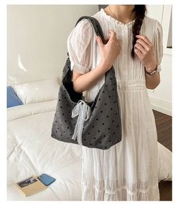 Close-up of dark grey polka dot canvas tote bag with white lace bow detail