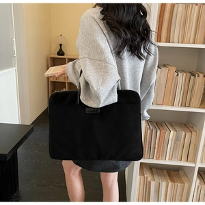 Modern black minimalist laptop bag held by a professional in a classic library setting