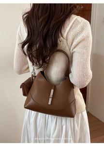 Detail view of caramel brown leather dumpling bag with silver clasp and mini charm