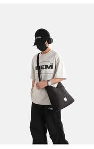 Grande borsa a tracolla in nylon nero indossata con un outfit casual in stile streetwear