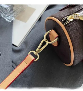 Close-up of golden metal buckle and brown textured leather on a crossbody bag