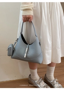 Detail of light blue bucket bag with pebble leather texture and silver buckle accessory