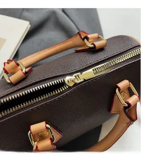 Close-up of brown lychee grain leather pillow bag with smooth metal zipper detail