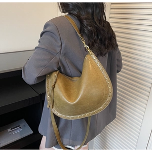 Detail of olive green crescent shoulder bag with metallic gold studs and leather strap