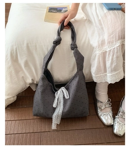 Detailed close-up of grey polka dot canvas tote bag with white lace bow and knotted strap