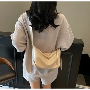 Minimalist beige dumpling bag with soft pleated leather texture shown on model shoulder