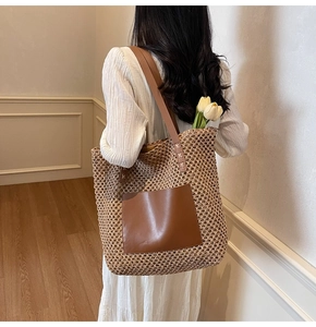 Detail of straw tote bag featuring deep brown leather pocket and woven natural fiber texture