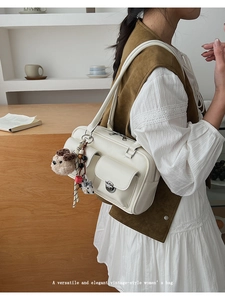 Detail of vintage cream shoulder bag featuring silver buckles and cute plush puppy charm