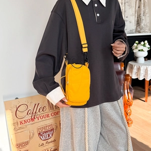 Detail of bright yellow nylon crossbody bag with adjustable strap in a cafe setting