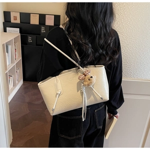 Dettaglio della borsa tote off-white con trama in pelle plissettata e ciondolo a orsetto