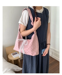 Close-up of pink polka dot canvas tote with lace bow detail and knotted shoulder strap