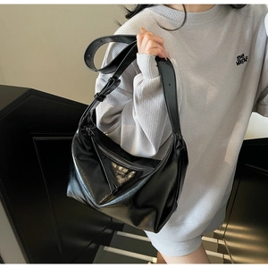 Detail of minimalist black glossy hobo bag with soft texture and wide shoulder strap