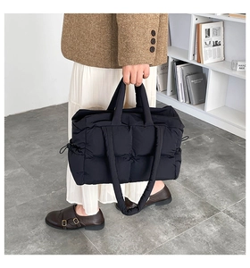 Detail of black quilted puffer tote bag with square stitching and side drawstring