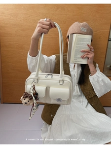 Close-up of vintage white shoulder bag with dual front pockets and plush bear charm