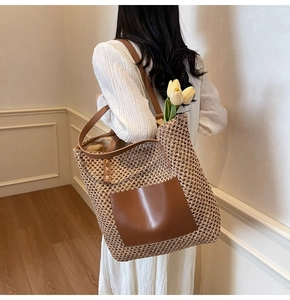 Detail of woven straw tote bag with brown leather straps and front pocket detail