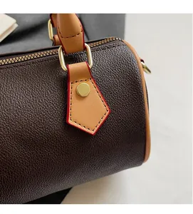 Detailed close-up of dark brown lychee texture leather with gold hardware and red edge paint