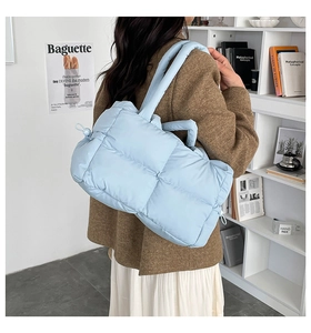 Detail of light blue quilted down shoulder bag with drawstring closure and soft texture