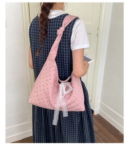 Detail of pink polka dot canvas tote bag with side lace bow and knotted strap design