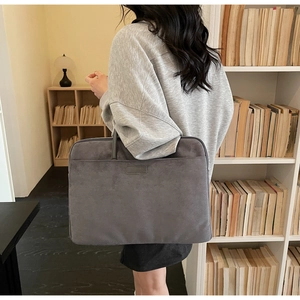 Detail of grey suede-like business laptop bag carried in a cozy bookstore setting