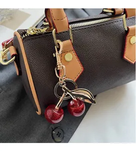 Close-up of vintage brown leather handbag with gold zipper and sequined cherry charm