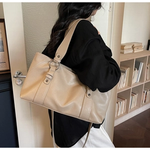 Detail of beige faux leather tote bag with silver round hardware and adjustable strap