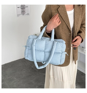 Quilted light blue puffer tote bag shown on model with shoulder strap and drawstring details