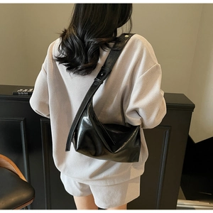 Detail view of glossy black faux leather hobo bag with a wide adjustable shoulder strap