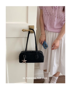 Detail of black Boston bag featuring a silver star charm on a white wooden door