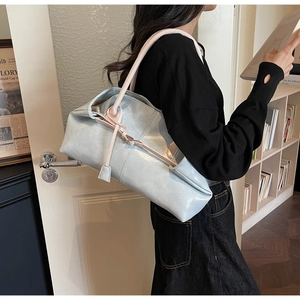 Détail latéral du sac cabas en cuir bleu avec anses contrastées porté par un mannequin femme