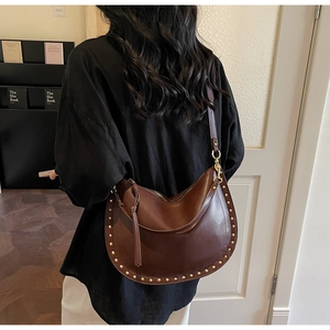 Detail of dark brown crescent bag with gold stud rivets in a retro bohemian style