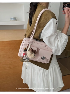 Pink vintage shoulder bag with front flap pockets, metal buckles, and cute plush pendants