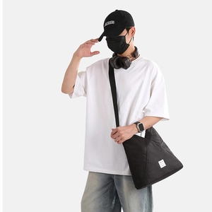 Borsa a tracolla minimalista in nylon nero mostrata in stile urbano casual su un modello