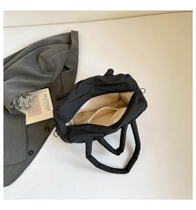 Detail view of black puffer tote bag interior with beige lining and internal pocket