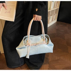 Gros plan du sac cabas en cuir bleu clair avec anses crème et boucle en métal vintage
