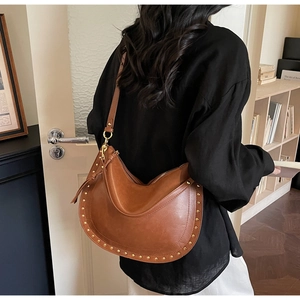 Detailed view of brown leather hobo bag with gold stud rivets and stylish shoulder strap