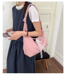 Detailed close-up of a pink polka dot canvas tote bag featuring a decorative lace bow